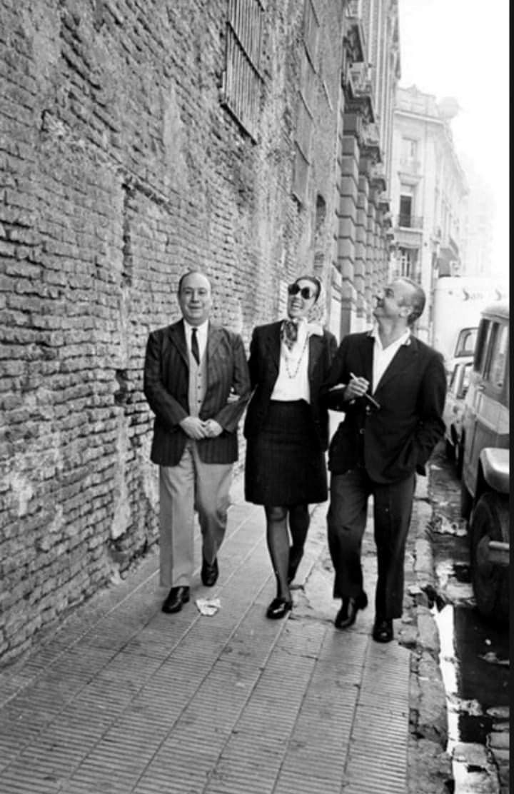 Astor Piazzolla · Susana Rinaldi · Leopoldo Marechal — Leopoldo Marechal, Susana Rinaldi y Astor Piazzolla caminando junto a un desconchado paredón de San Telmo a fines de los años 60.