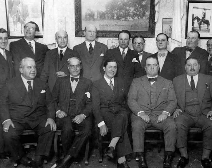 Sentado sonriente vemos en 1933 al cantor Carlos Gardel en una reunión celebrada en el club “Leales y Pampeanos” de Avellaneda.